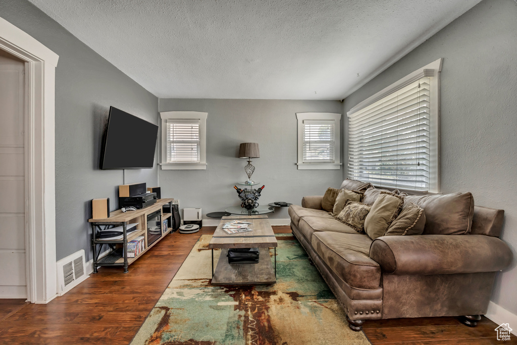 Living room with wood finished floors, a textured ceiling, healthy amount of natural light, and baseboards