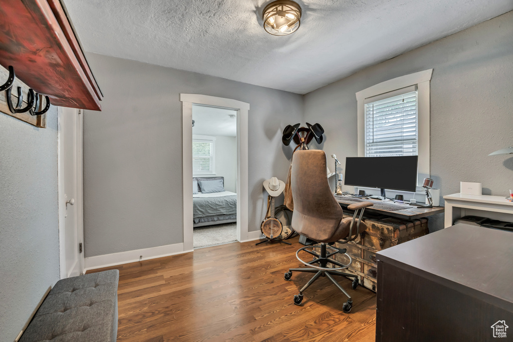 Home office featuring wood finished floors, a textured ceiling, and baseboards