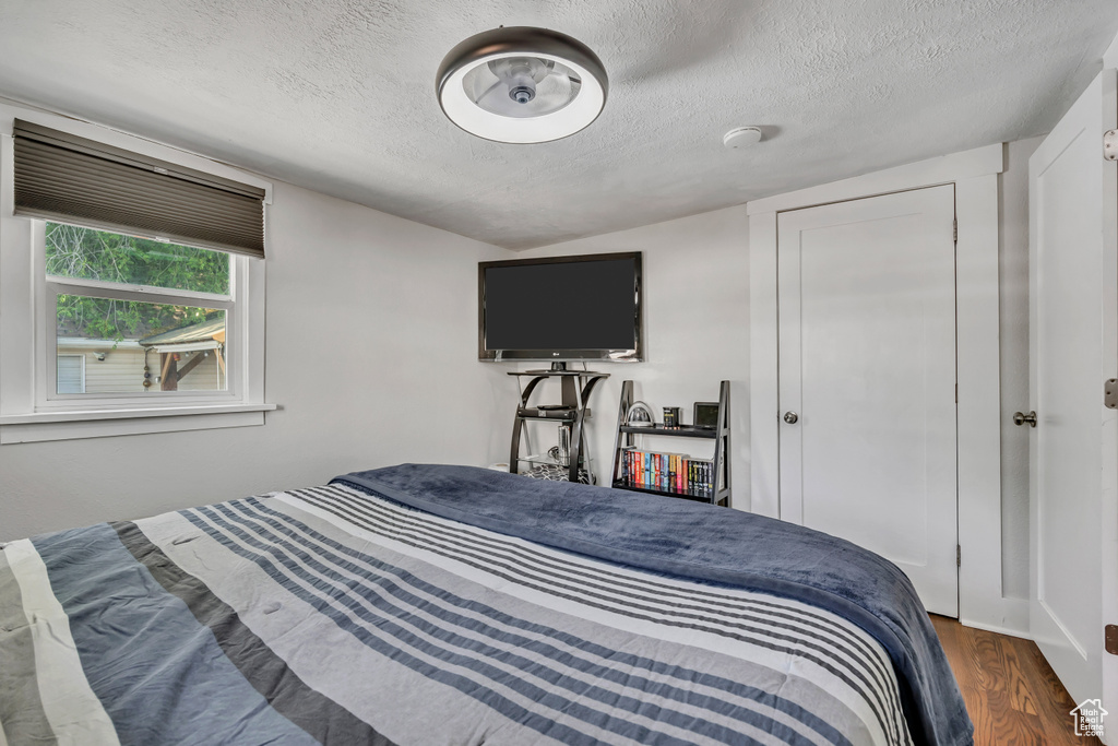 Bedroom with a textured ceiling and wood finished floors