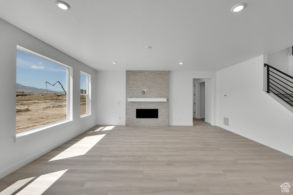Unfurnished living room featuring recessed lighting, a fireplace, light wood-type flooring, baseboards, and a mountain view