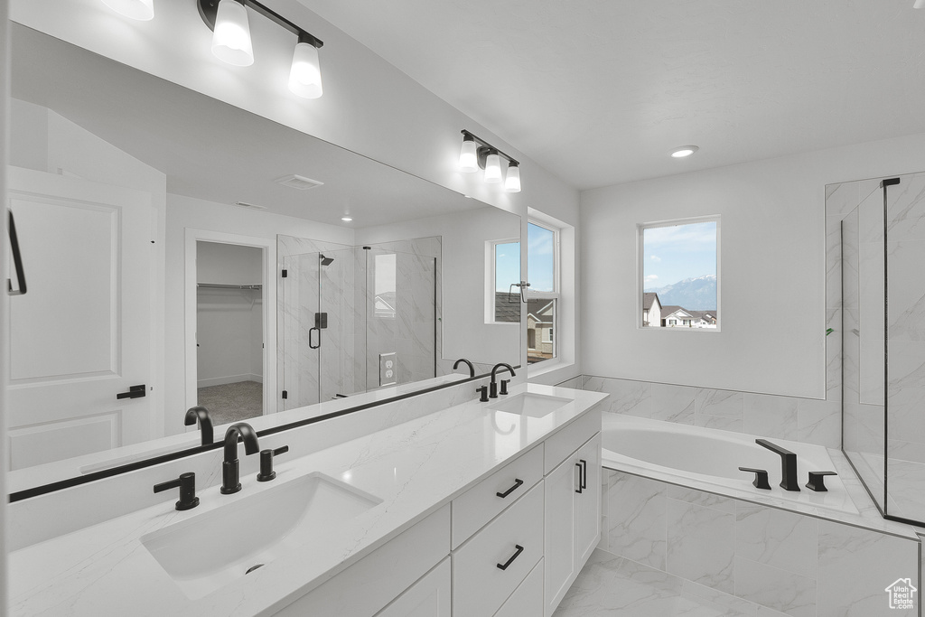 Bathroom featuring a bath, a marble finish shower, double vanity, recessed lighting, and a spacious closet