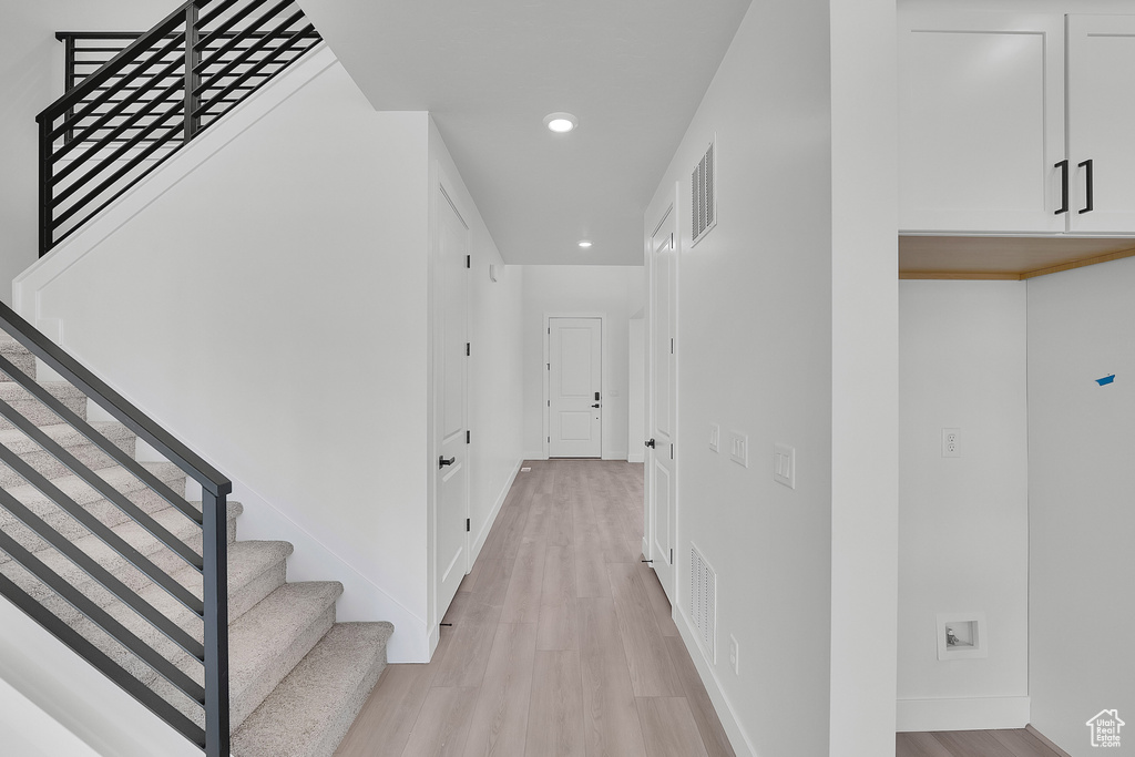 Hallway with recessed lighting, light wood-style flooring, baseboards, and stairway