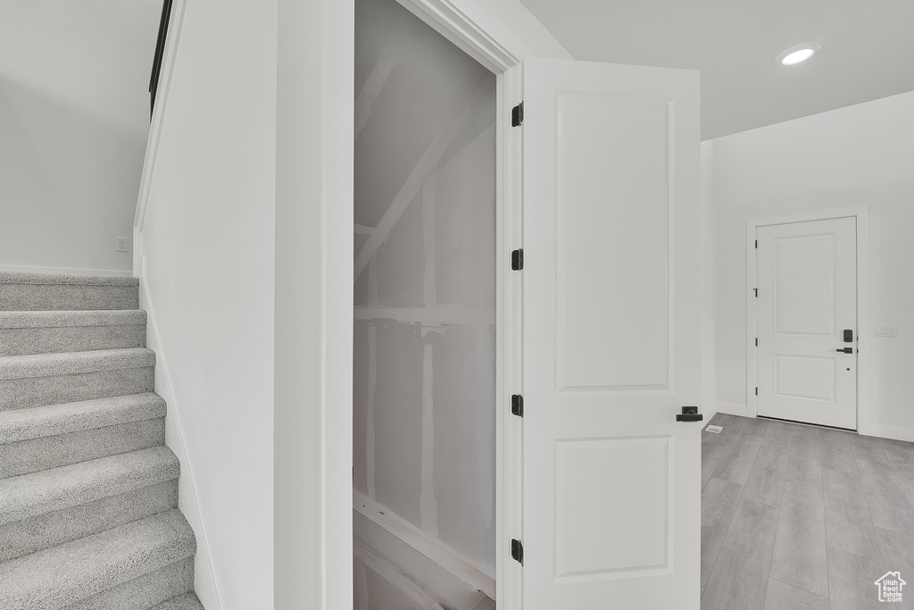 Stairway with recessed lighting, baseboards, and wood finished floors