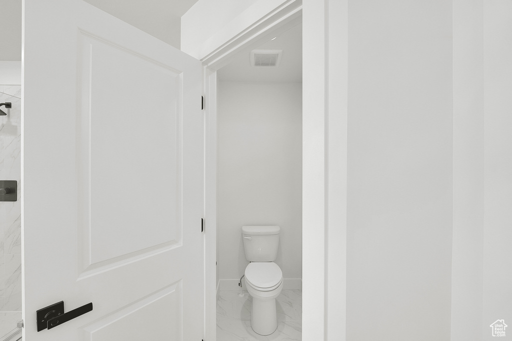Bathroom with marble finish flooring, toilet, and baseboards