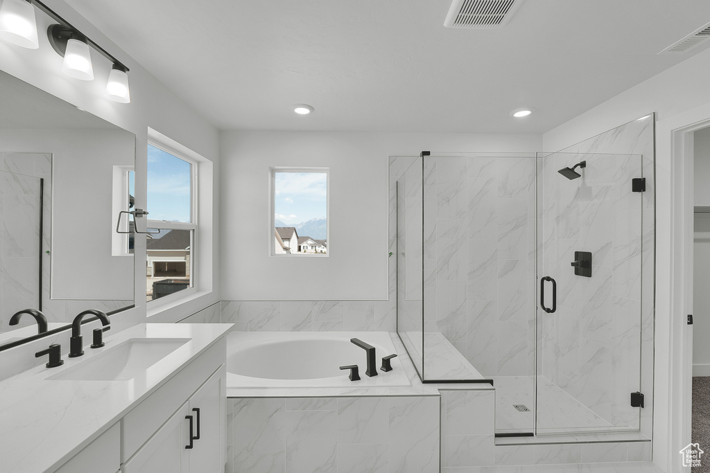 Bathroom featuring vanity, a bath, a marble finish shower, and recessed lighting