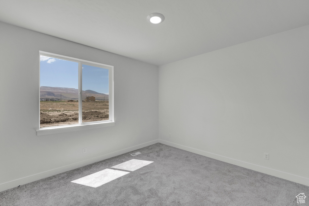 Empty room featuring carpet and baseboards