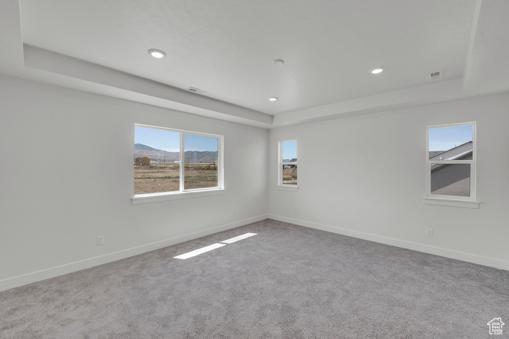 Carpeted empty room with a raised ceiling, baseboards, and recessed lighting