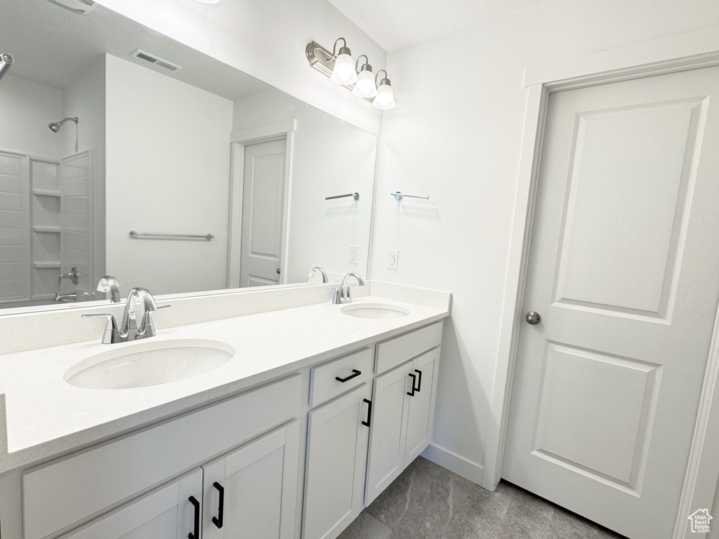 Full bathroom with double vanity, baseboards, and washtub / shower combination