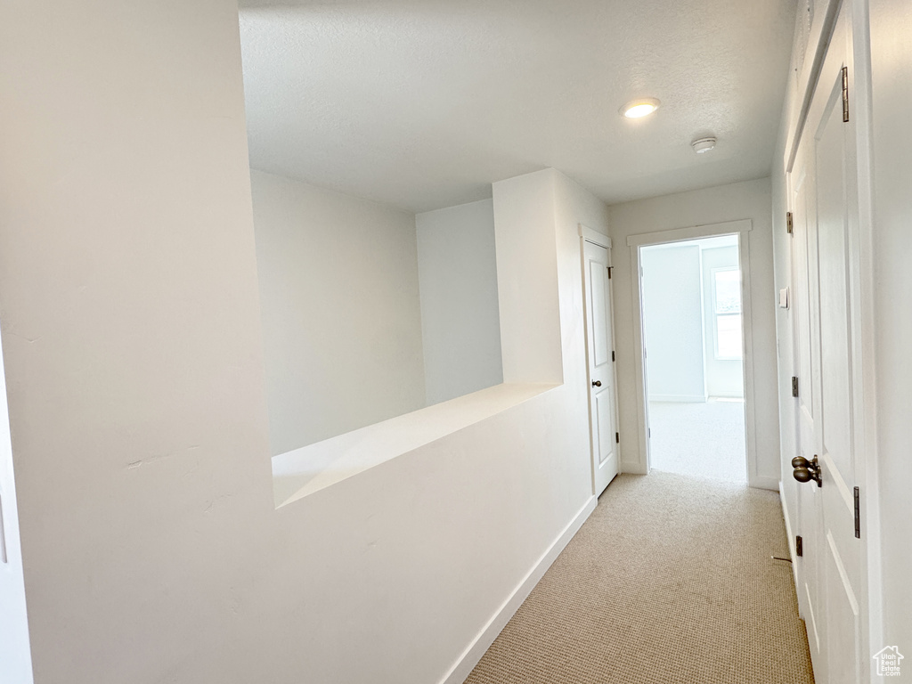 Hallway featuring light carpet, baseboards, and recessed lighting