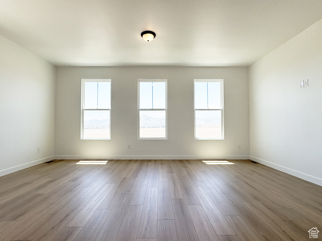Unfurnished room featuring plenty of natural light, wood finished floors, and baseboards