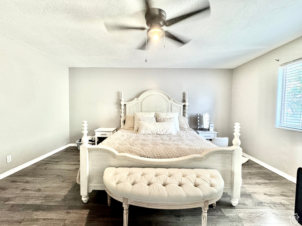Bedroom featuring wood finished floors, baseboards, a textured ceiling, and ceiling fan