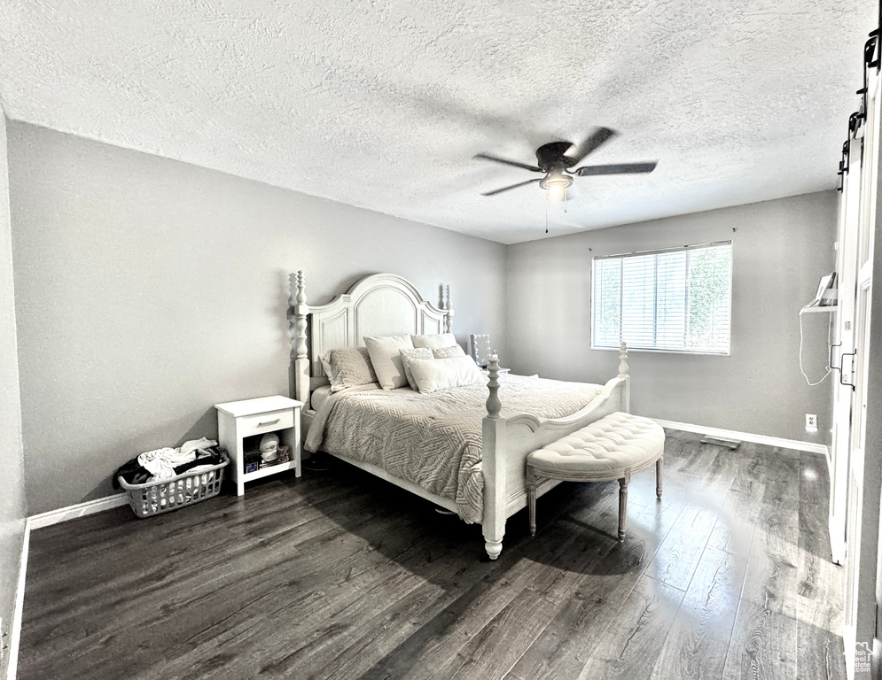 Bedroom featuring baseboards, dark wood finished floors, ceiling fan, and a textured ceiling
