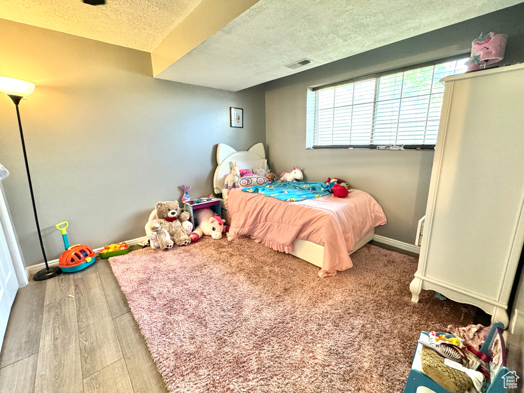 Bedroom with a textured ceiling, wood finished floors, and baseboards
