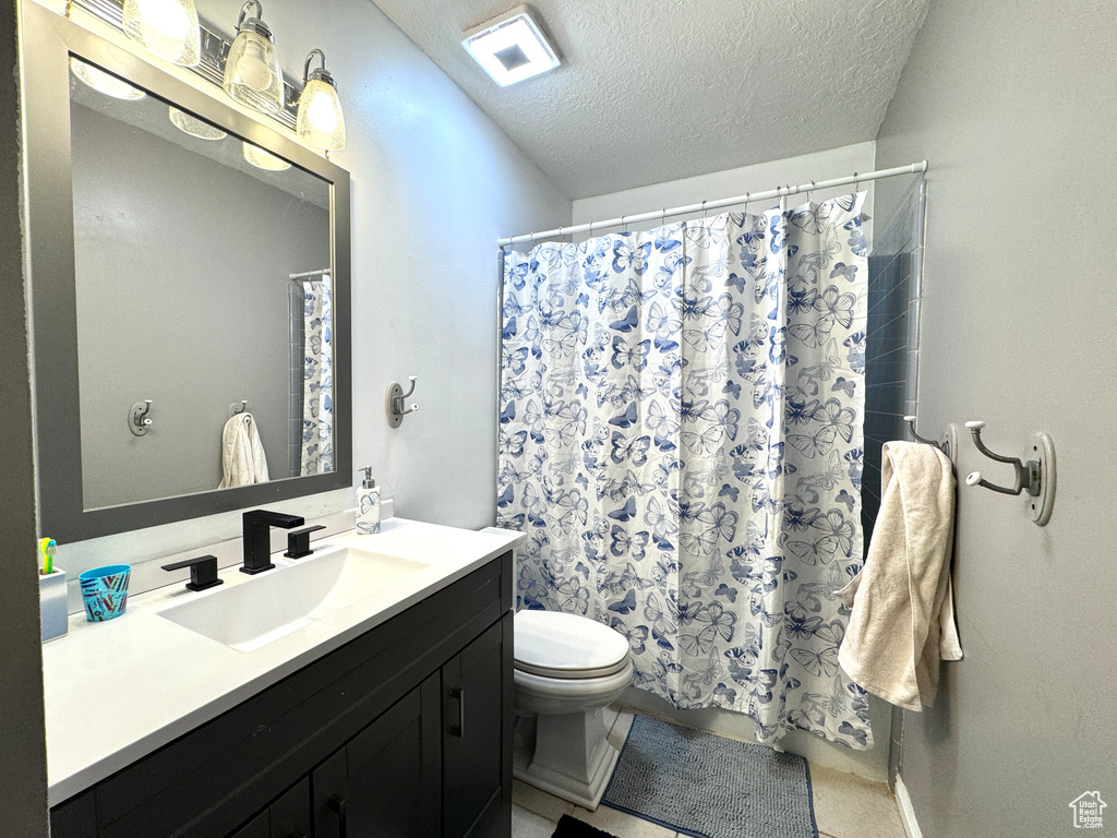 Full bathroom featuring vanity, toilet, a textured ceiling, a shower with shower curtain, and tile patterned flooring