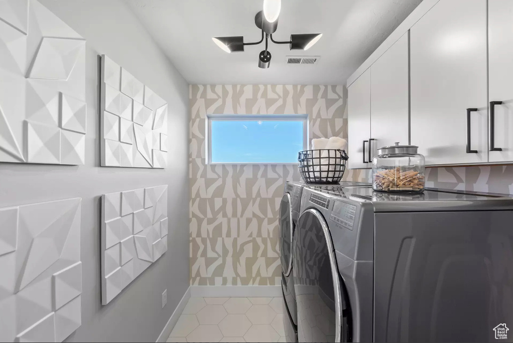 Washroom featuring independent washer and dryer, cabinet space, baseboards, wallpapered walls, and light tile patterned floors