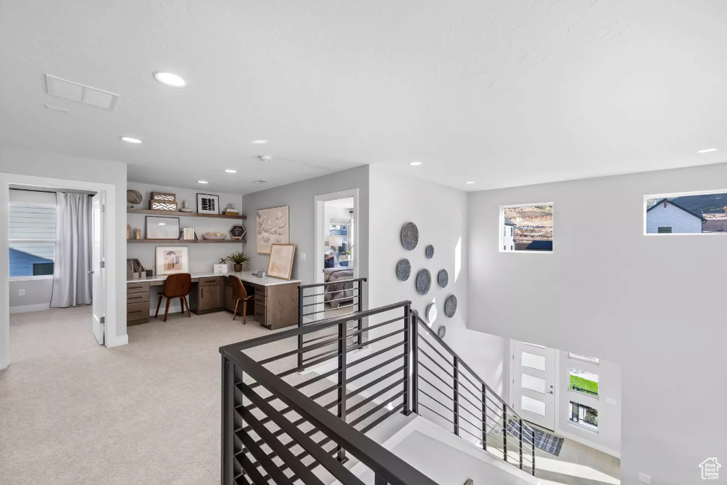 Stairway with recessed lighting, carpet flooring, and built in desk