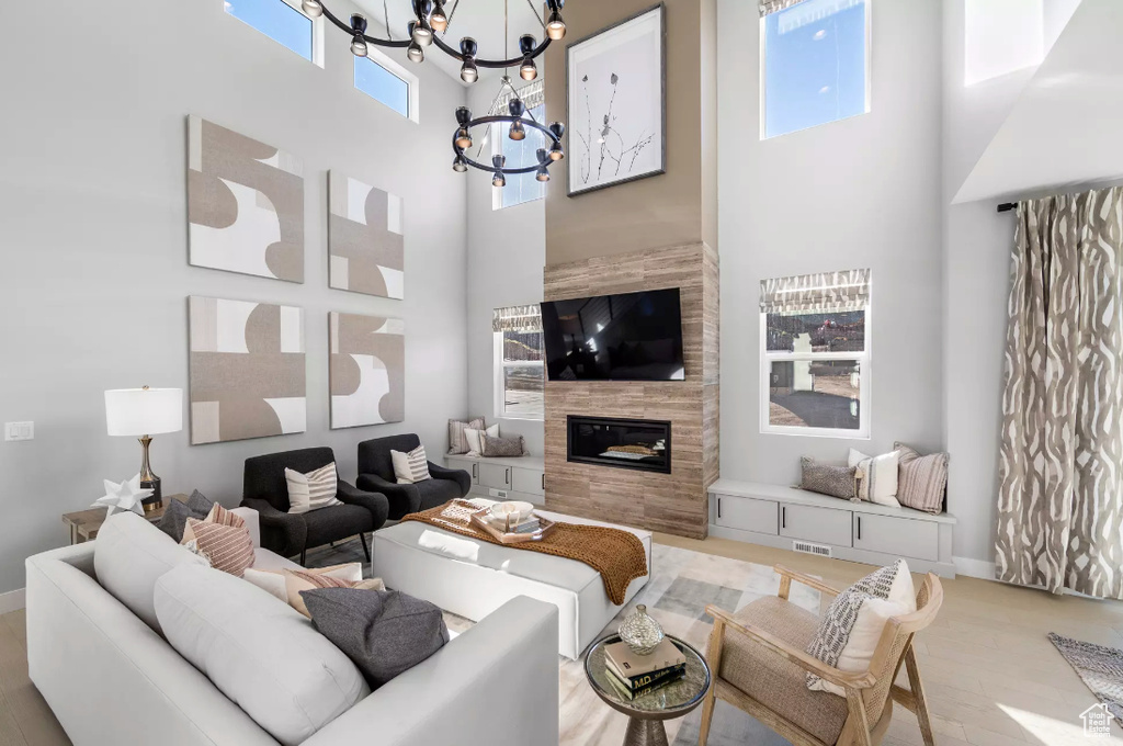Living area with a high ceiling, a chandelier, a tile fireplace, and baseboards