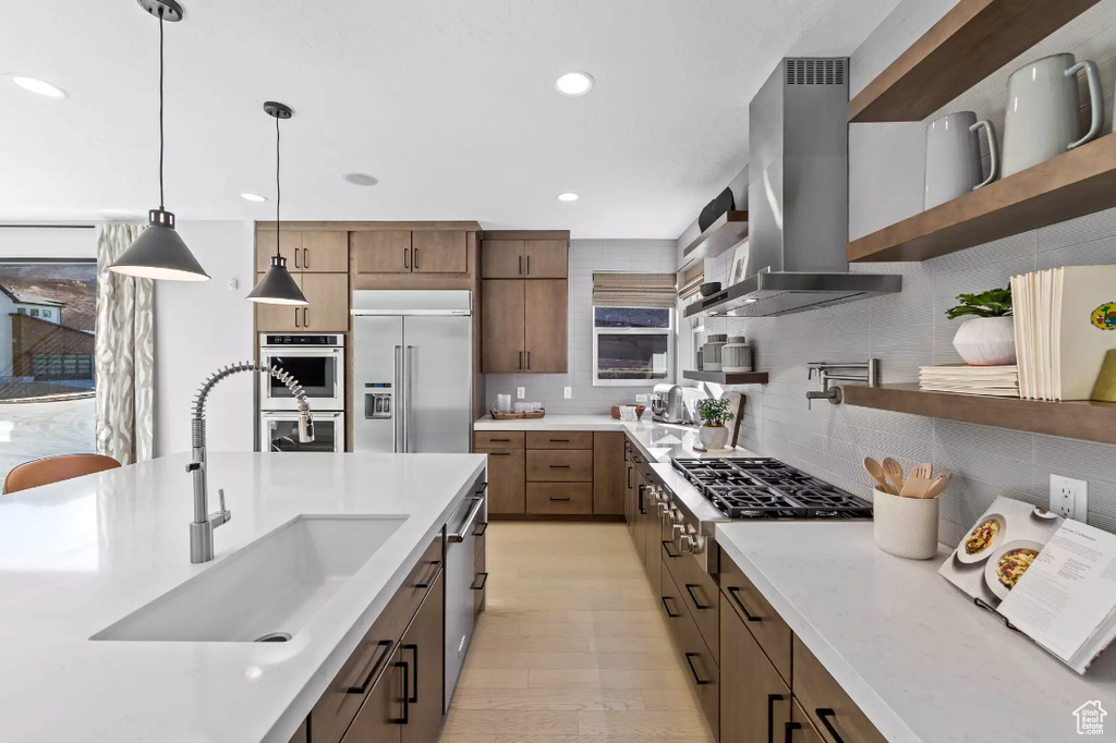 Kitchen with island exhaust hood, open shelves, stainless steel appliances, a sink, and tasteful backsplash