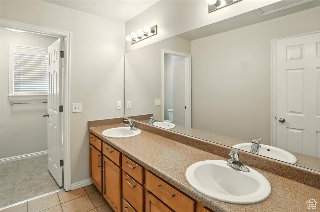 Bathroom with double vanity, tile patterned flooring, toilet, and baseboards