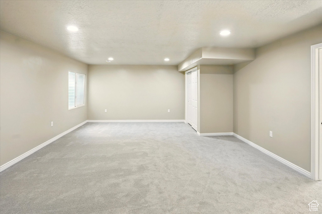 Below grade area with recessed lighting, carpet floors, baseboards, and a textured ceiling
