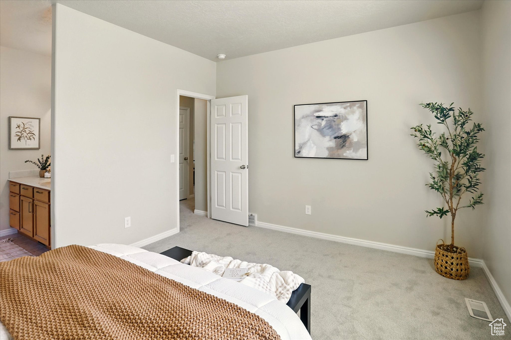 Bedroom featuring light carpet, baseboards, and ensuite bath