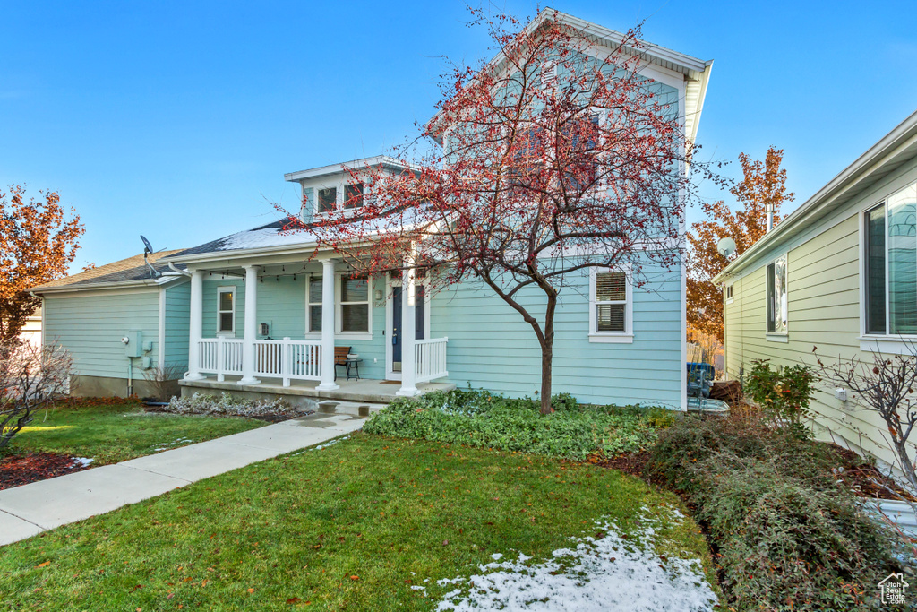 View of front of property featuring covered porch and a front yard