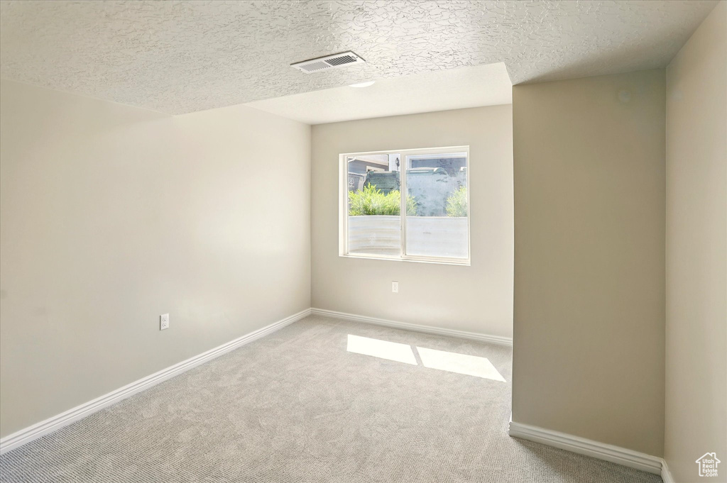 Empty room featuring carpet floors, a textured ceiling, and baseboards