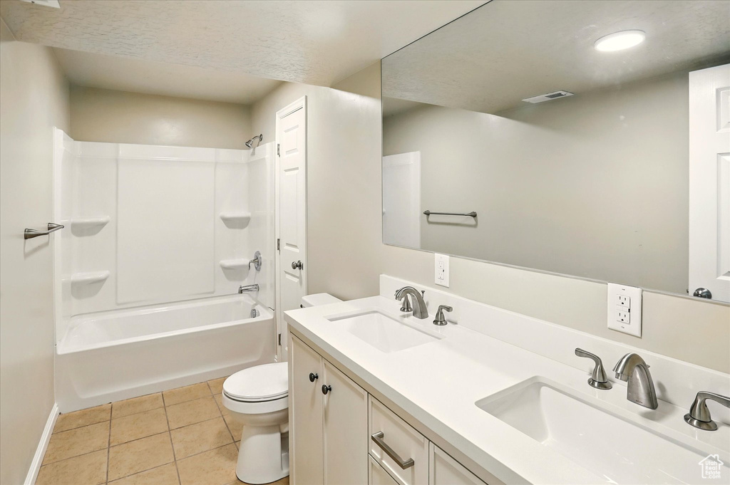 Bathroom featuring toilet, double vanity, tile patterned floors, baseboards, and tub / shower combination