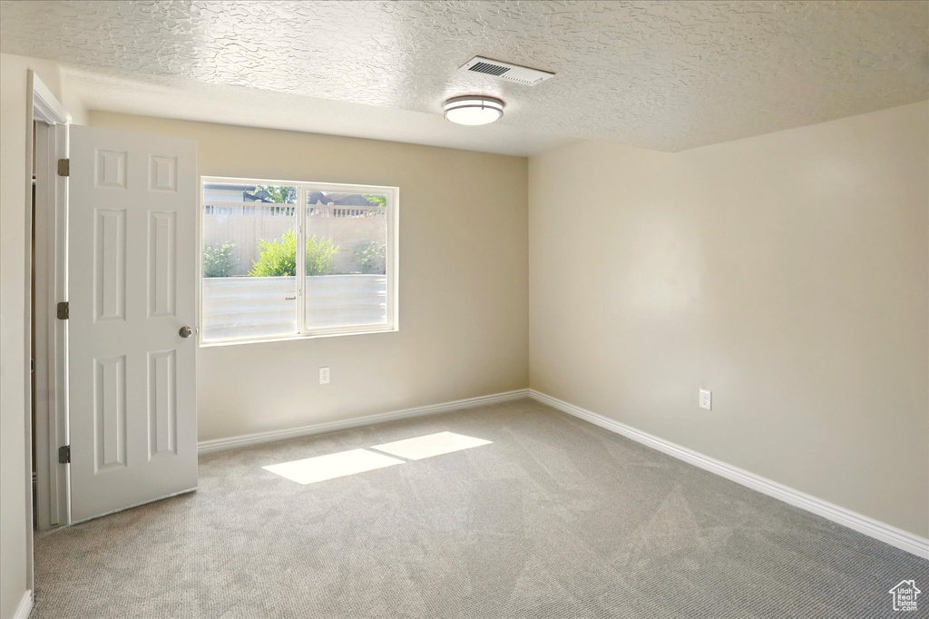 Carpeted spare room featuring baseboards and a textured ceiling