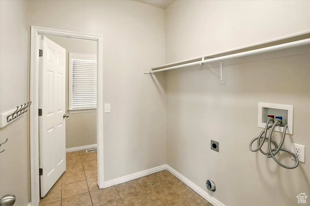 Laundry area with washer hookup, hookup for an electric dryer, baseboards, and light tile patterned floors