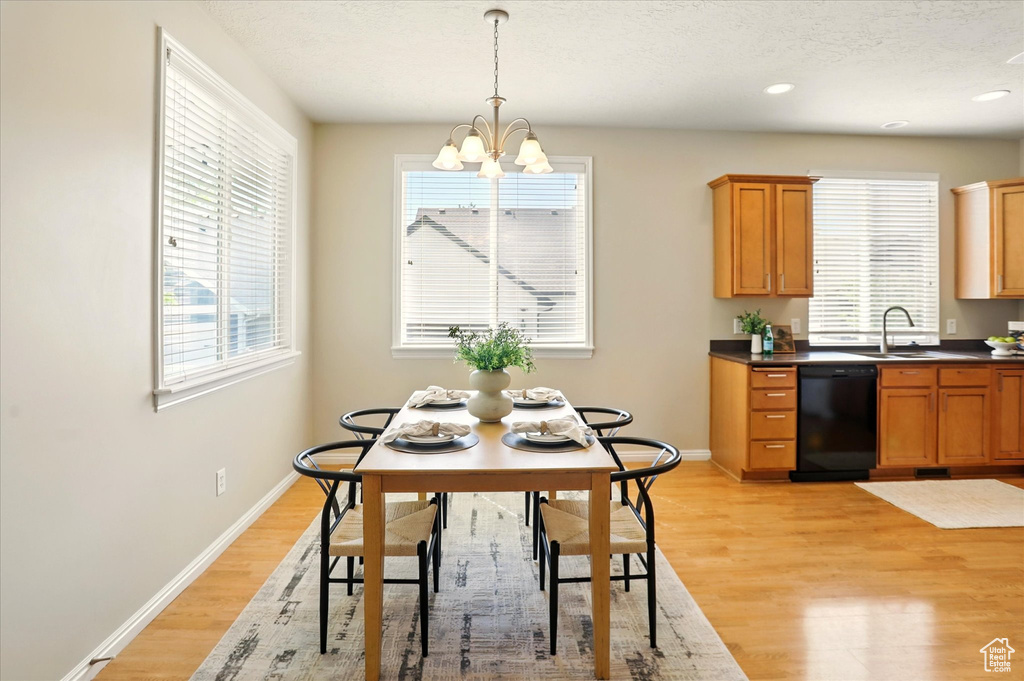 Dining space with a chandelier, light wood finished floors, baseboards, and recessed lighting