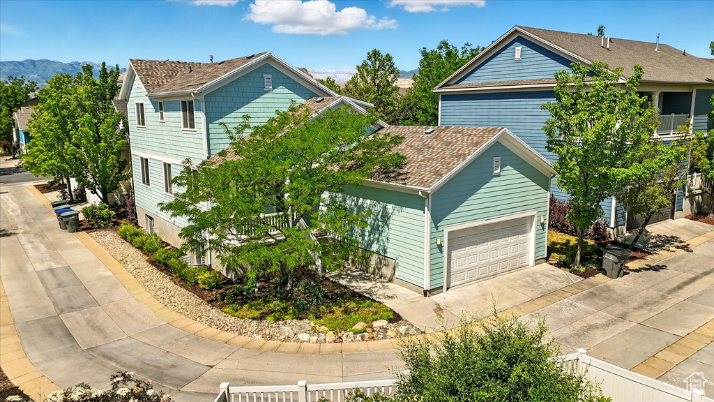 View of front of house with a garage, concrete driveway, a mountain view, and a shingled roof