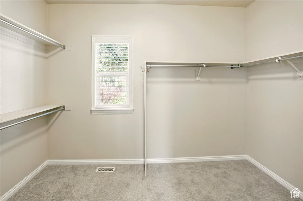 Walk in closet featuring light colored carpet
