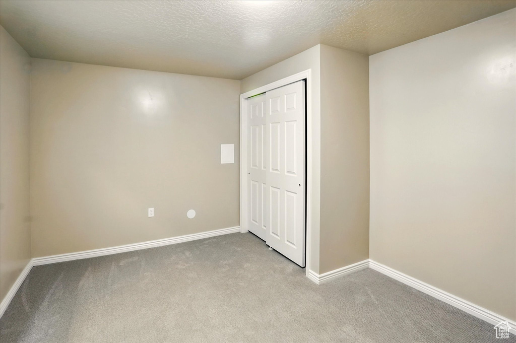 Unfurnished bedroom featuring carpet floors, baseboards, a closet, and a textured ceiling