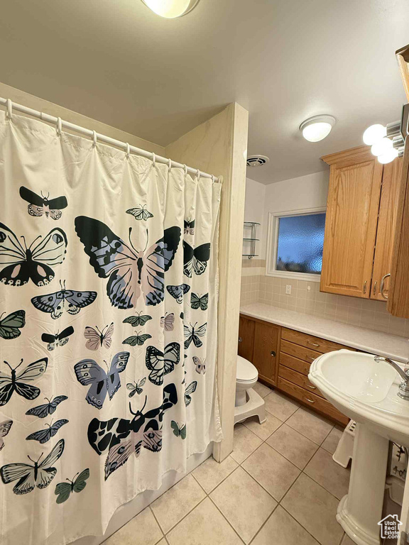 Full bath featuring toilet, tile patterned floors, decorative backsplash, and a shower with shower curtain
