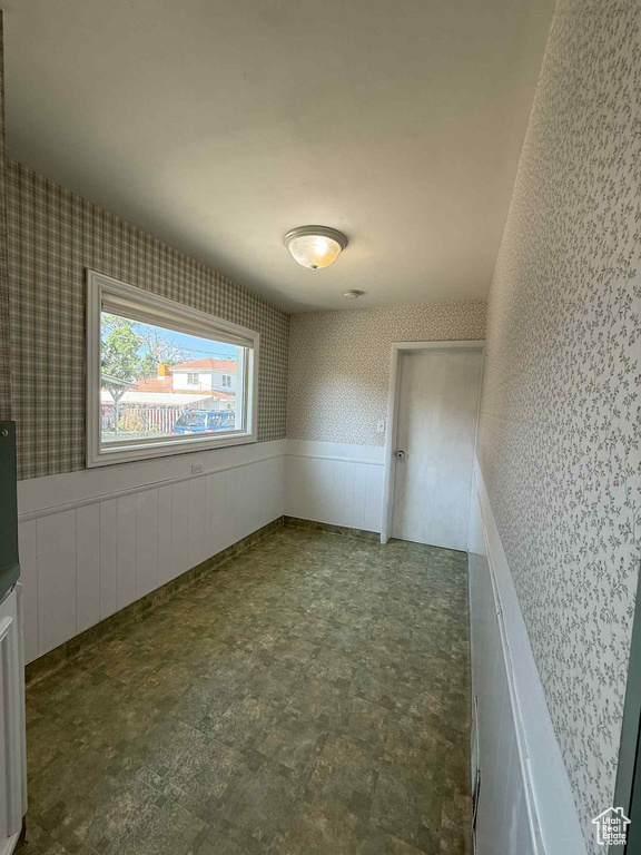 Empty room featuring wallpapered walls and wainscoting