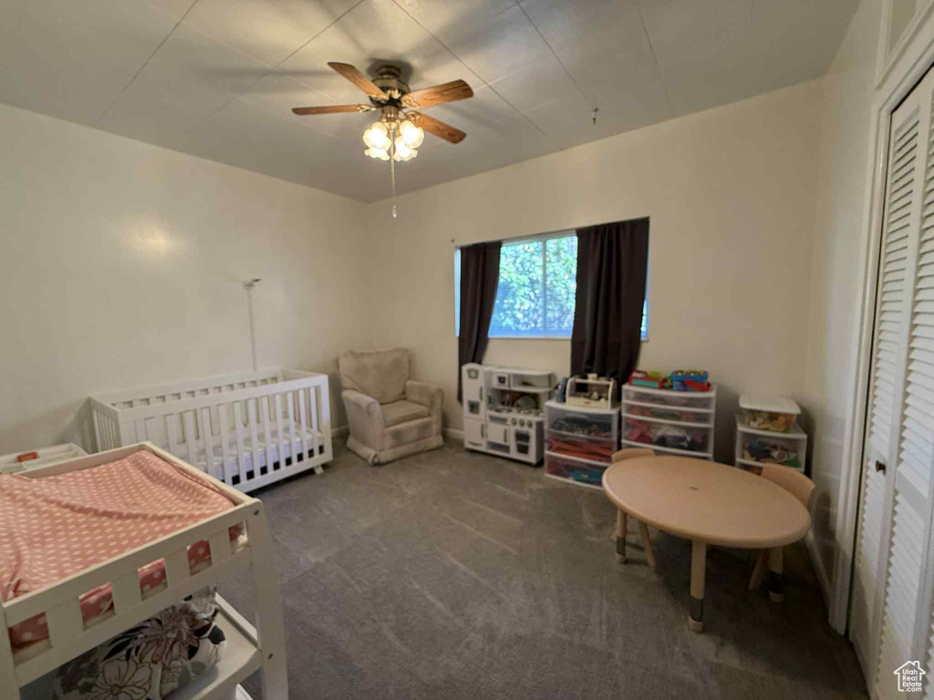 Bedroom with carpet flooring, a closet, radiator heating unit, ceiling fan, and a nursery area