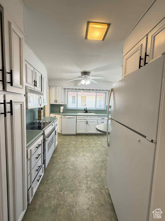 Kitchen featuring white appliances, a sink, ceiling fan, white cabinetry, and light countertops