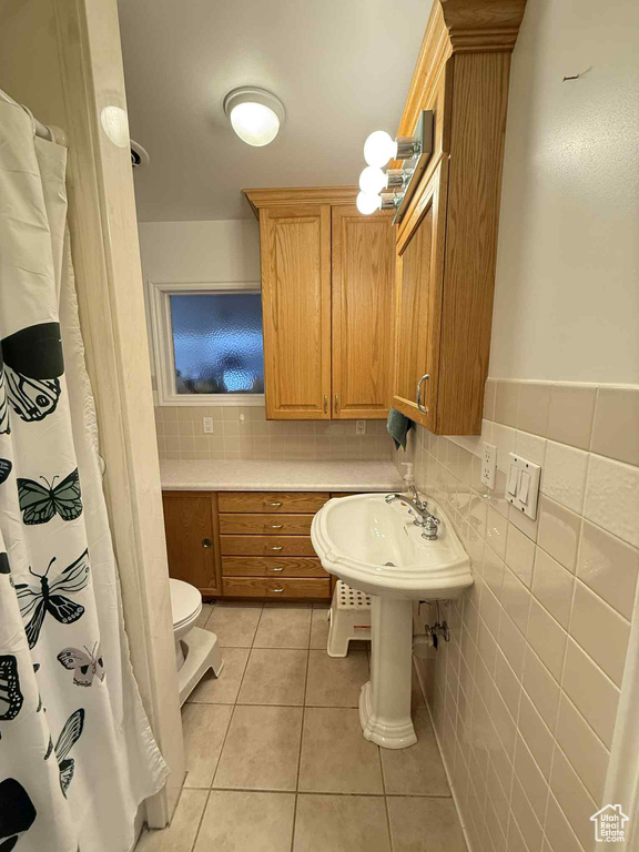 Bathroom with tile patterned floors, toilet, and backsplash