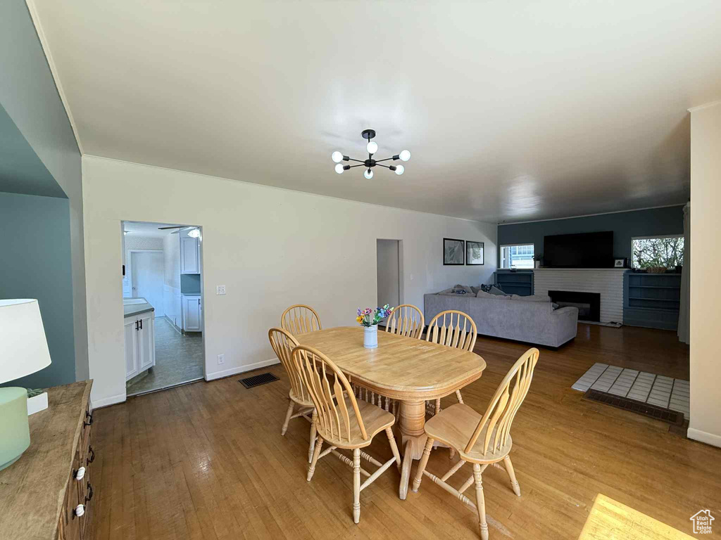 Dining space featuring a chandelier, wood finished floors, baseboards, and a fireplace