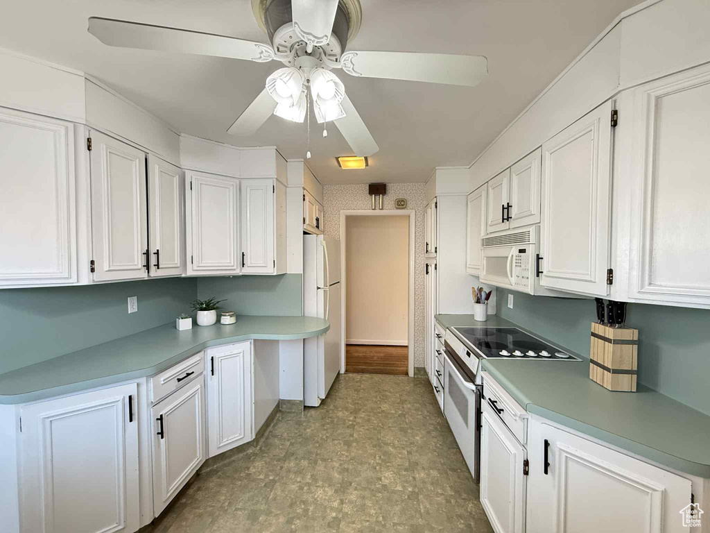 Kitchen with white appliances, ceiling fan, white cabinets, and light countertops