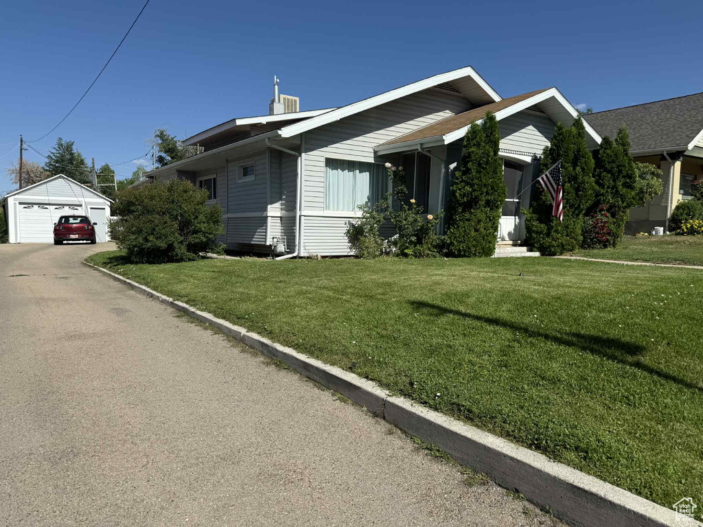 View of front of house featuring a garage, an outbuilding, and a front yard