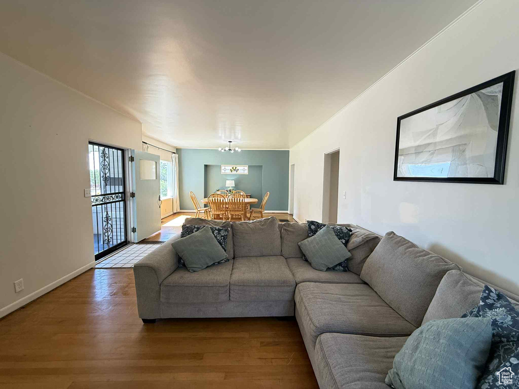 Living area with dark wood-type flooring, a chandelier, and baseboards