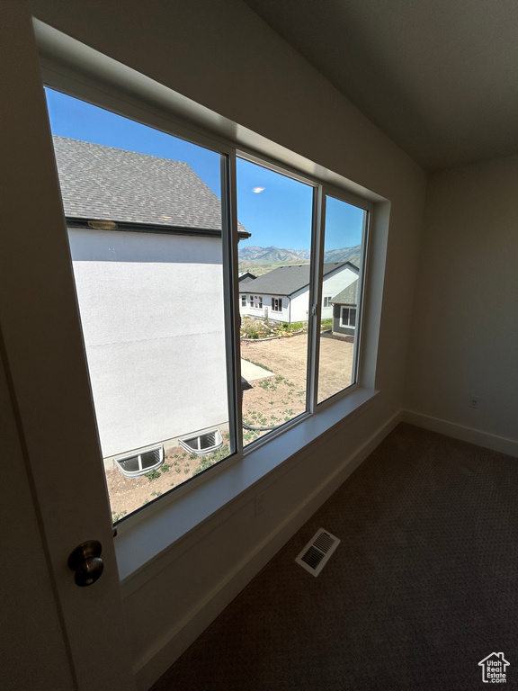 Empty room featuring dark colored carpet and baseboards
