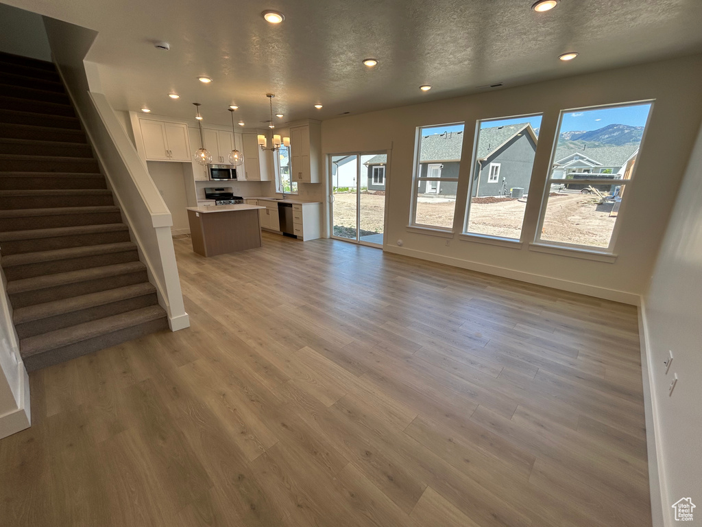 Unfurnished living room featuring baseboards, recessed lighting, stairway, and light wood finished floors
