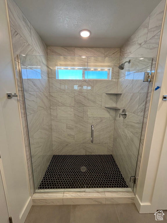 Full bathroom with healthy amount of natural light, a shower stall, and tile patterned floors