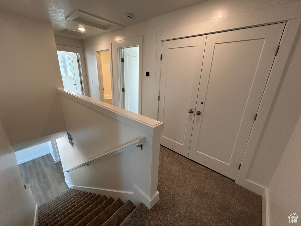 Hall with carpet flooring, attic access, baseboards, and an upstairs landing