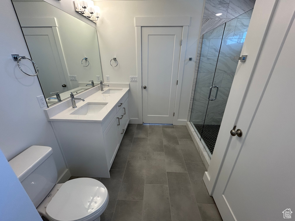 Full bathroom with a shower stall, double vanity, toilet, and tile patterned flooring