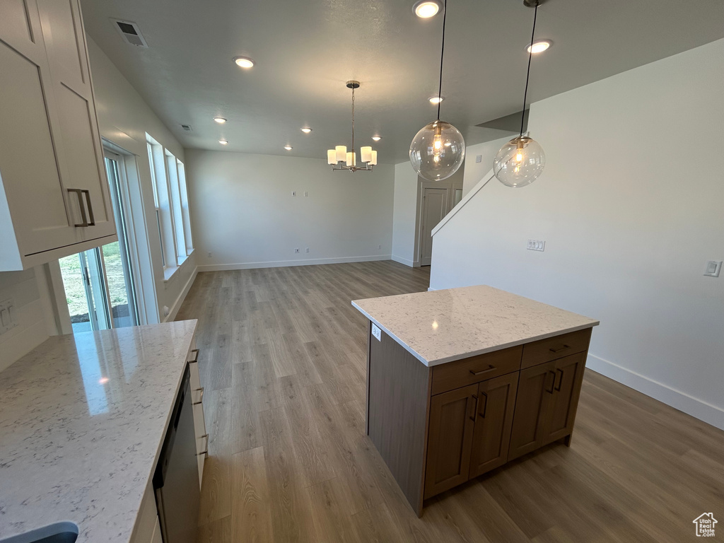 Kitchen with light wood-style floors, a chandelier, baseboards, light stone counters, and recessed lighting