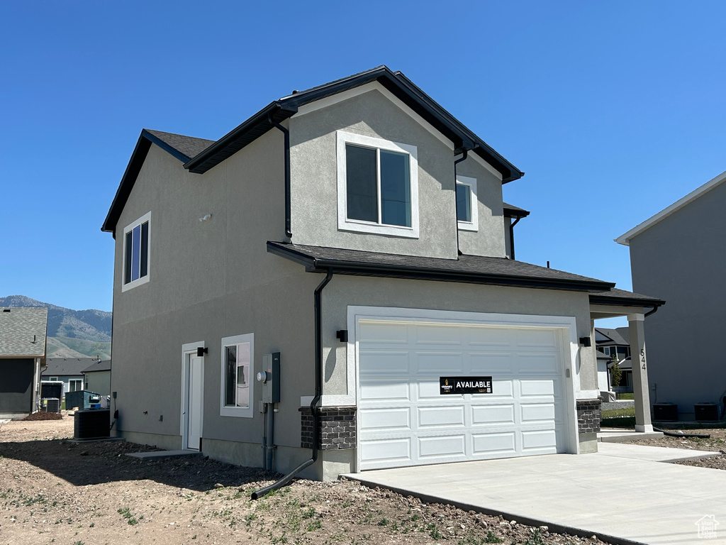 View of home's exterior with a garage, concrete driveway, stucco siding, and a mountain view